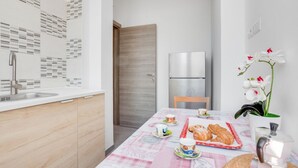 Una cucina moderna con un frigorifero in acciaio inossidabile, una porta in legno e un tavolo apparecchiato con pasticcini e tazze.