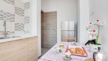 Una cucina moderna con un frigorifero in acciaio inossidabile, una porta in legno e un tavolo apparecchiato con pasticcini e tazze.