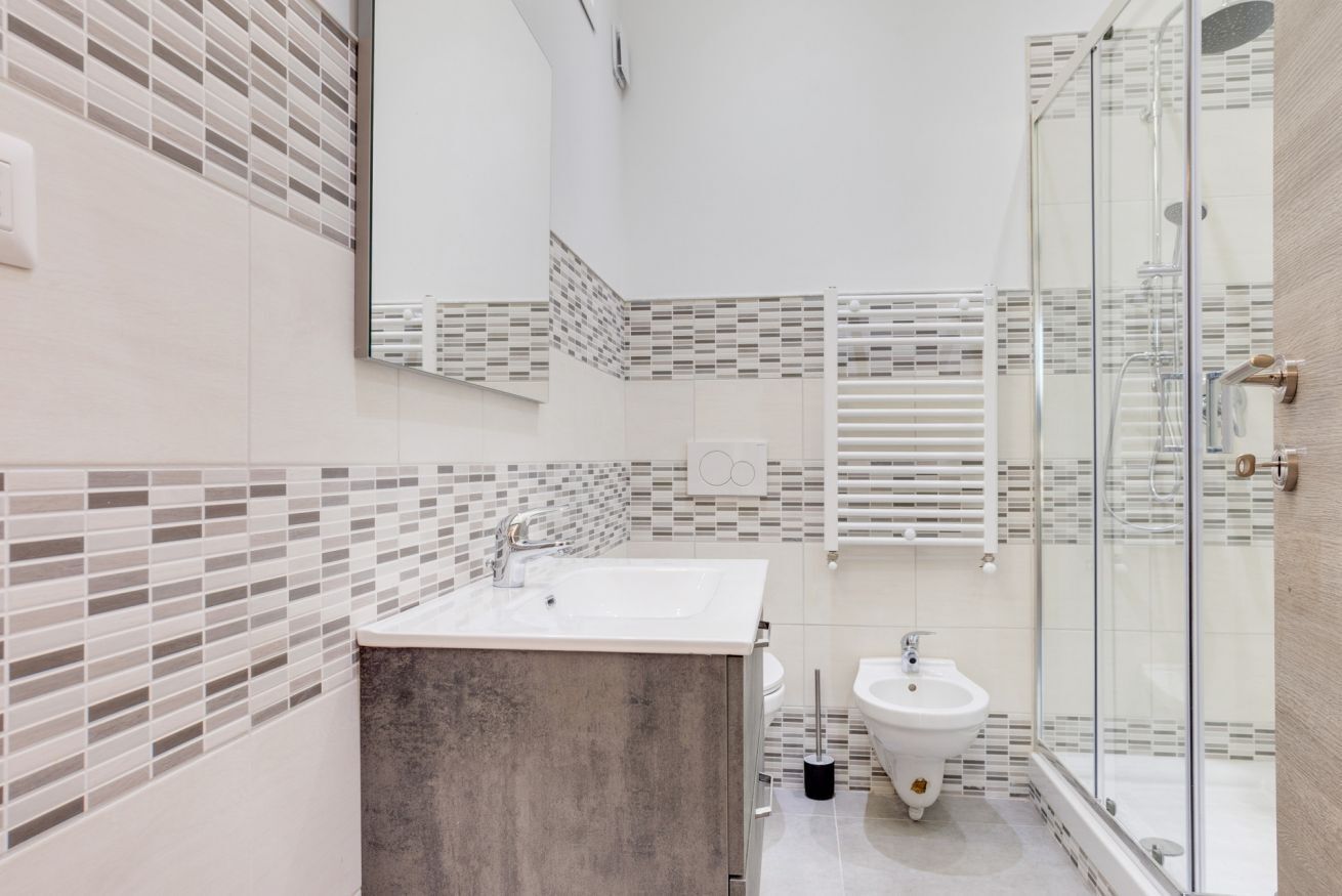 A modern bathroom with a glass shower enclosure, a sink, and a bidet.