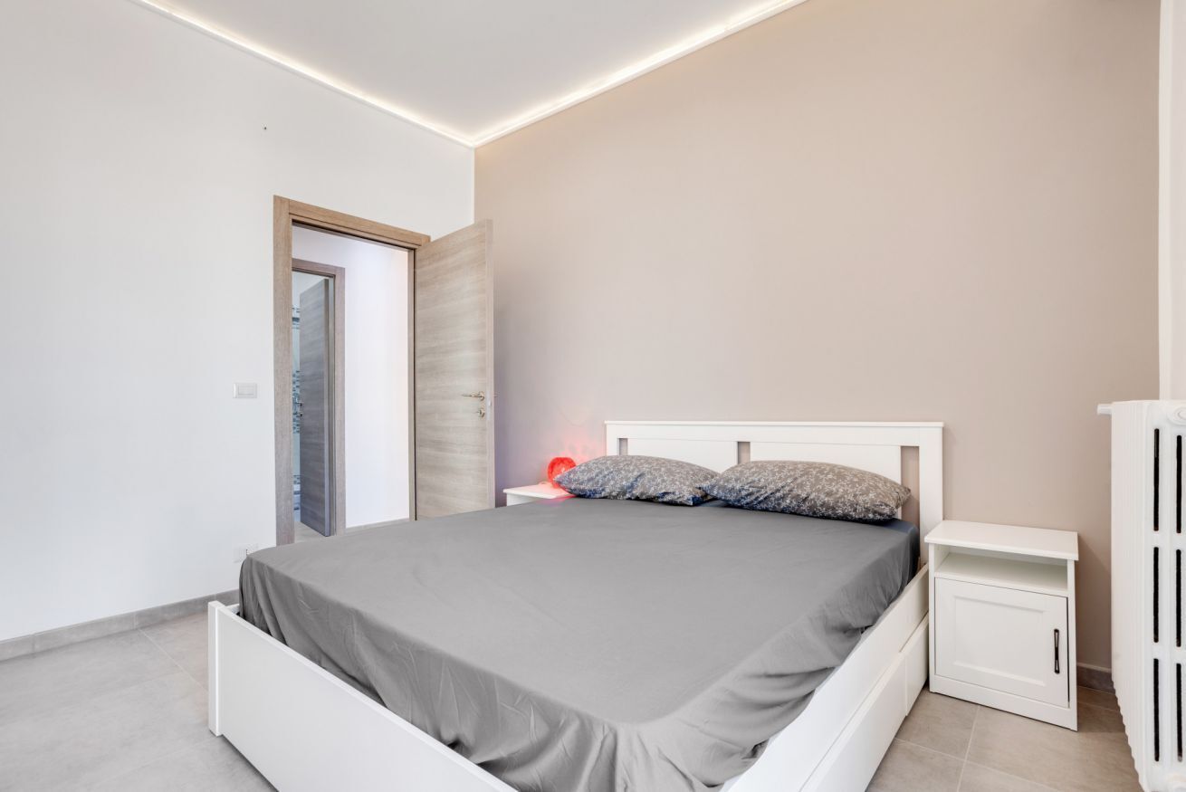 A modern bedroom with a bed, bedside tables, and a wardrobe.