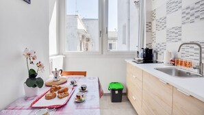 Una piccola cucina con una finestra, un lavandino, una moka e un cestino.