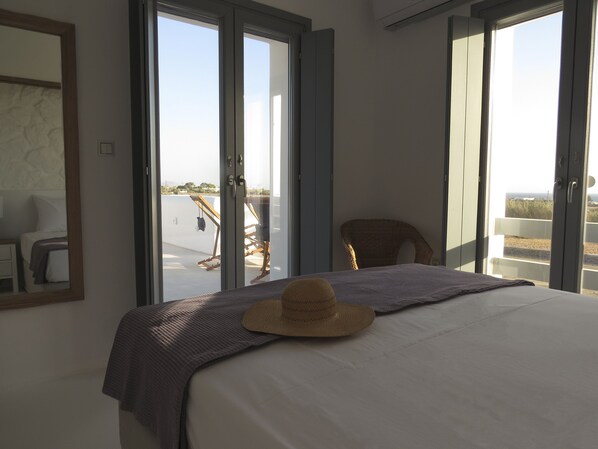Une chambre à coucher avec un lit, un chapeau posé sur le lit et une vue sur le balcon extérieur.