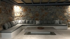 Un salon moderne avec un mur en pierre, un canapé d’angle et une table basse.