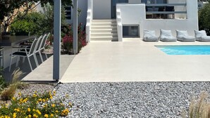 Une villa moderne de couleur blanche, dotée d’une piscine, d’un espace salon extérieur et d’un patio couvert.