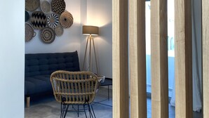 Una sala de estar moderna con un sofá oscuro, un sillón tejido, una lámpara de pie y decoración en la pared.