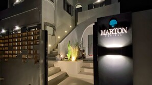 Un edificio moderno con una escalera que conduce a la entrada, un letrero con el nombre "MARTON PERISSA" y una planta de cactus cerca de los escalones.