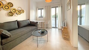 Una sala de estar moderna con un sofá, una mesa redonda y un comedor con una mesa y sillas blancas.