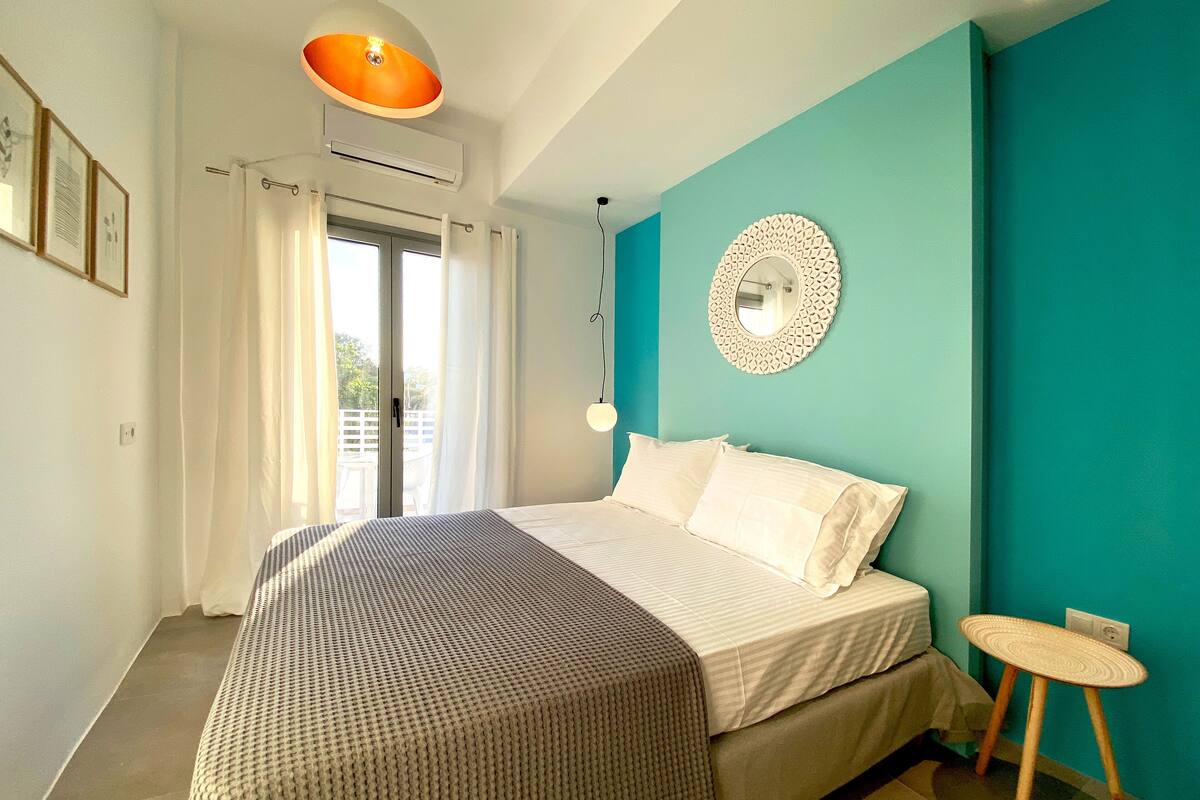 A bedroom with a bed, a ceiling light, a wall-mounted mirror, and a window with curtains.