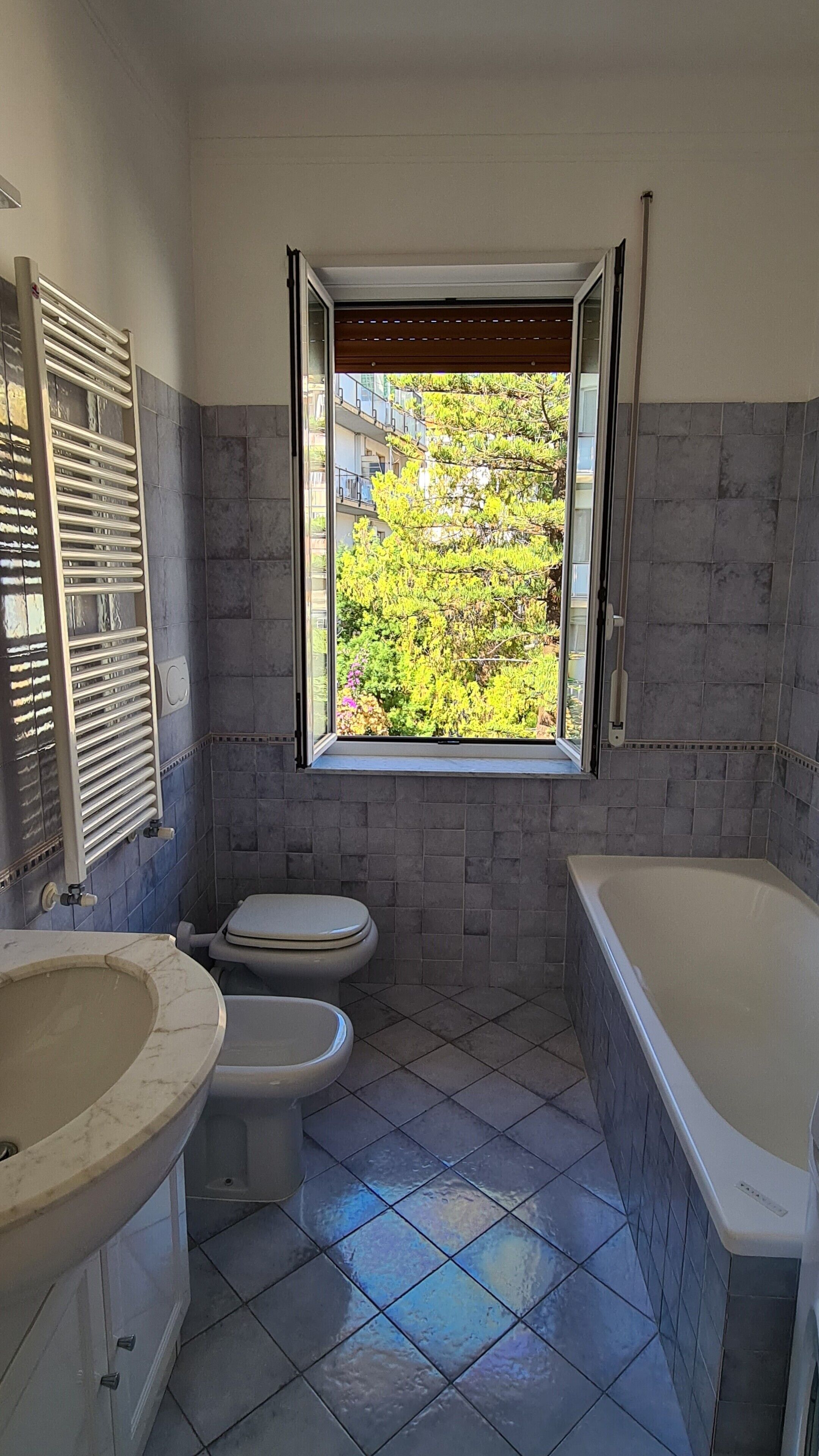 A bathroom with a window, a toilet, a sink, and a bathtub.