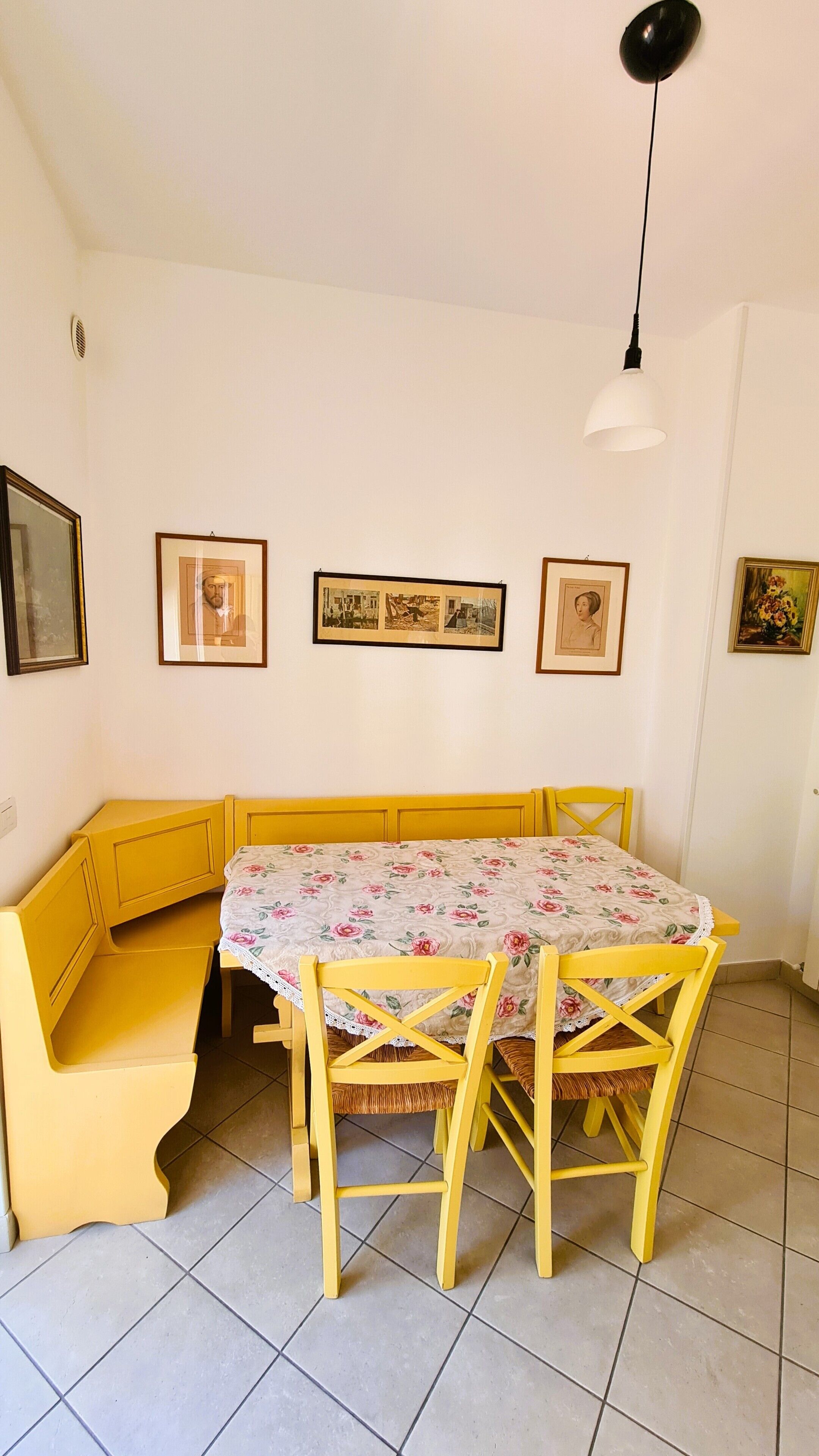 A dining area with a table and chairs, a bench, and framed pictures on the wall.