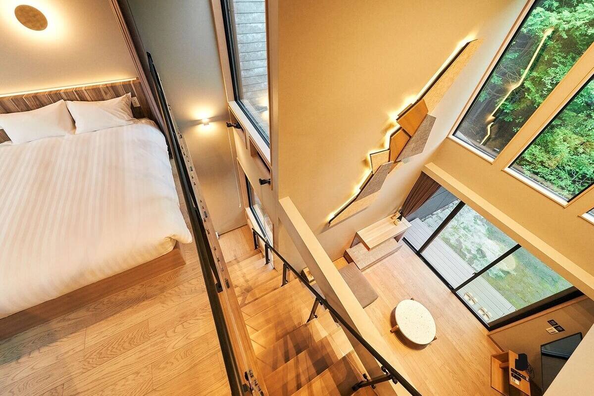 Una habitación de hotel moderna con una cama, un escritorio y vistas al exterior.