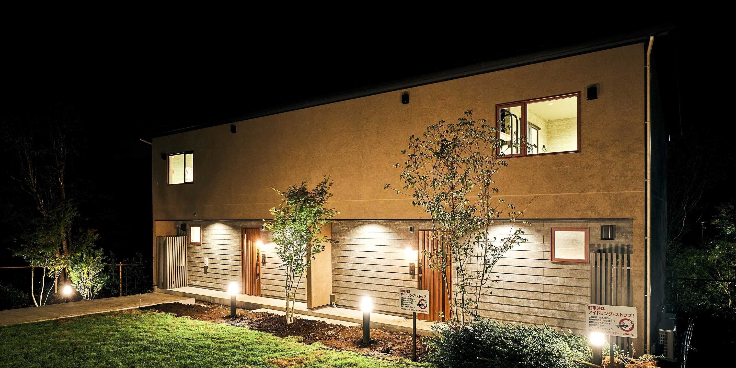A modern building with a flat roof, multiple doors, and a well-lit entrance.