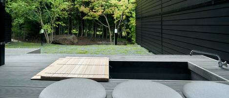 A deck with a built-in hot tub, wooden deck, and seating area.