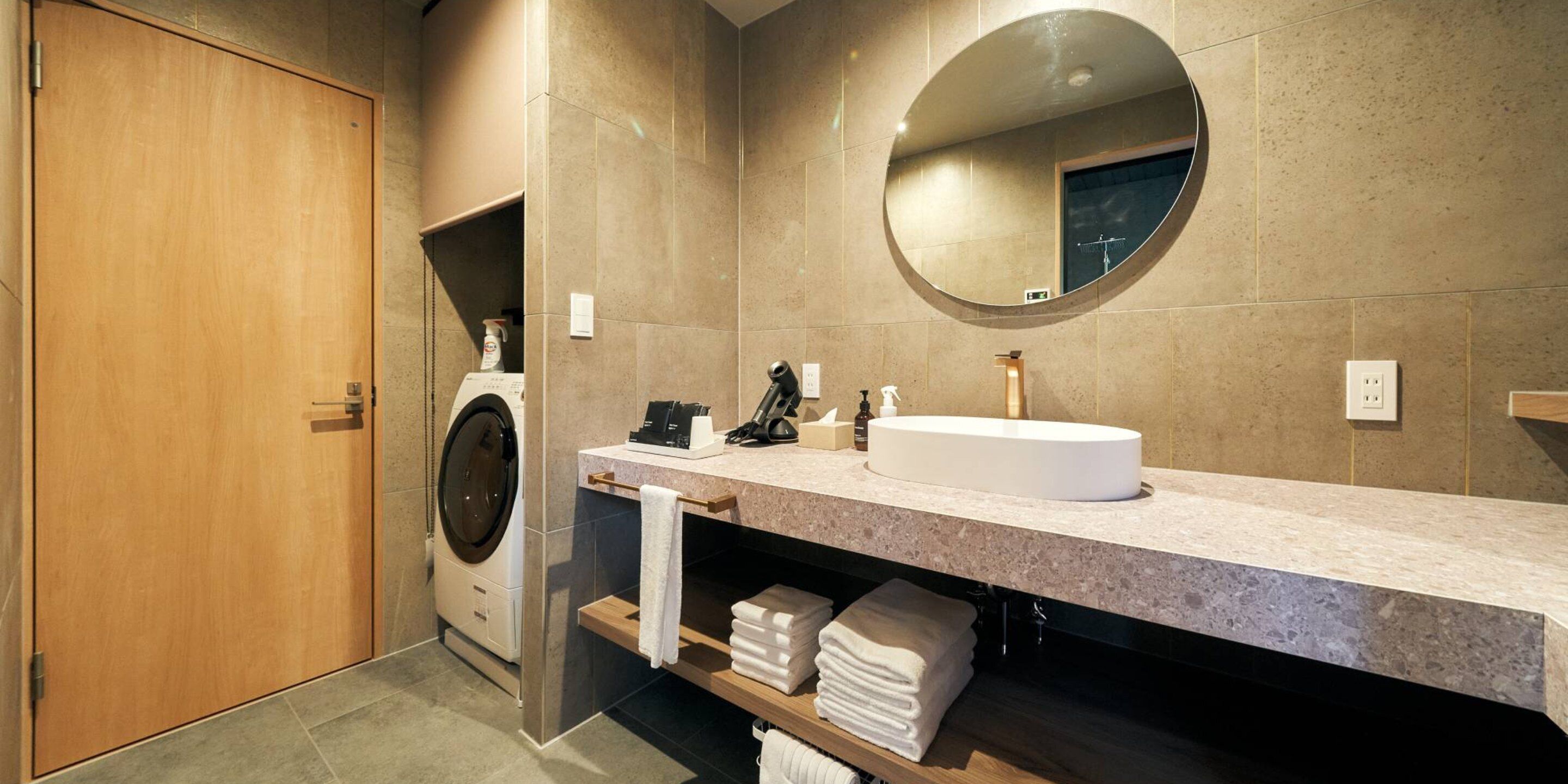 Ein modernes Badezimmer mit Waschmaschine, Waschbecken und Spiegel.