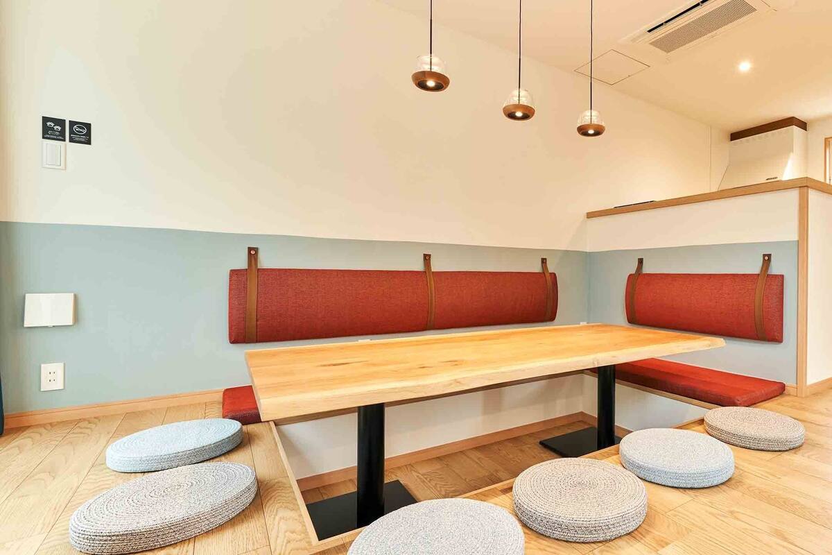 Una cocina moderna con una mesa de madera, asientos acolchados rojos y un refrigerador de acero inoxidable.