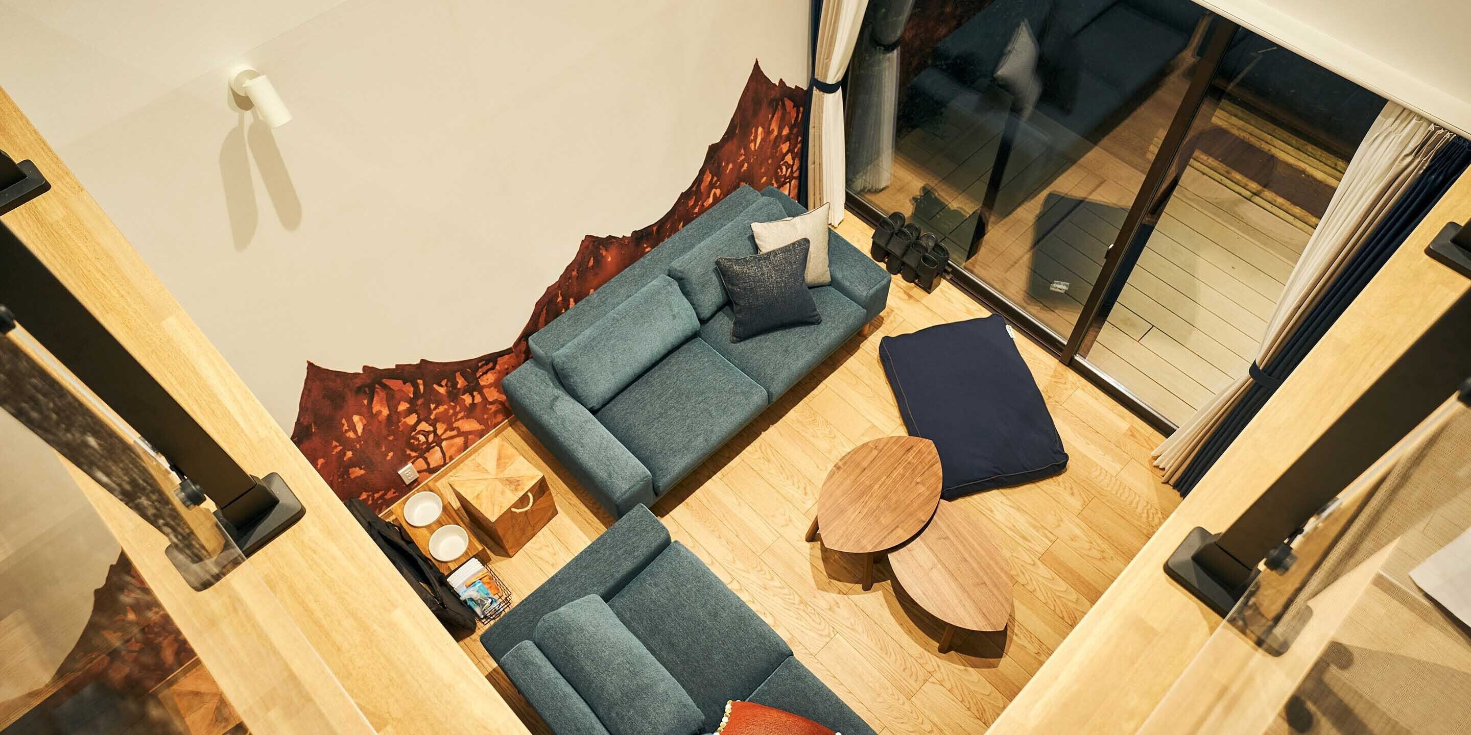 A modern living room with a sectional sofa, a round wooden coffee table, and a glass sliding door leading to an outdoor area.