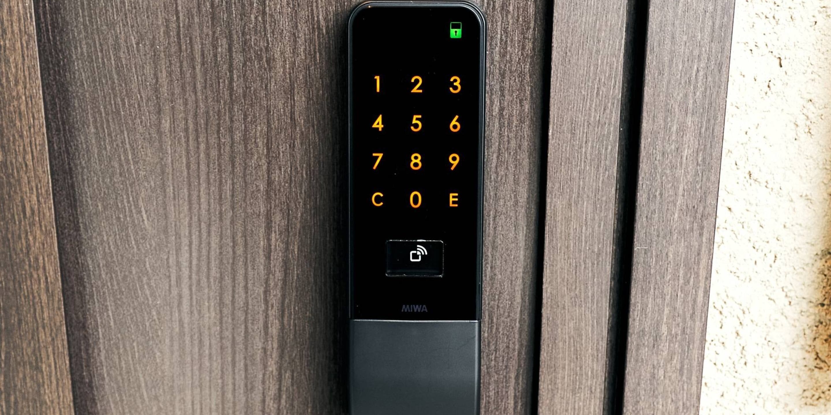 A black numeric keypad with a green lock icon on a wooden surface.