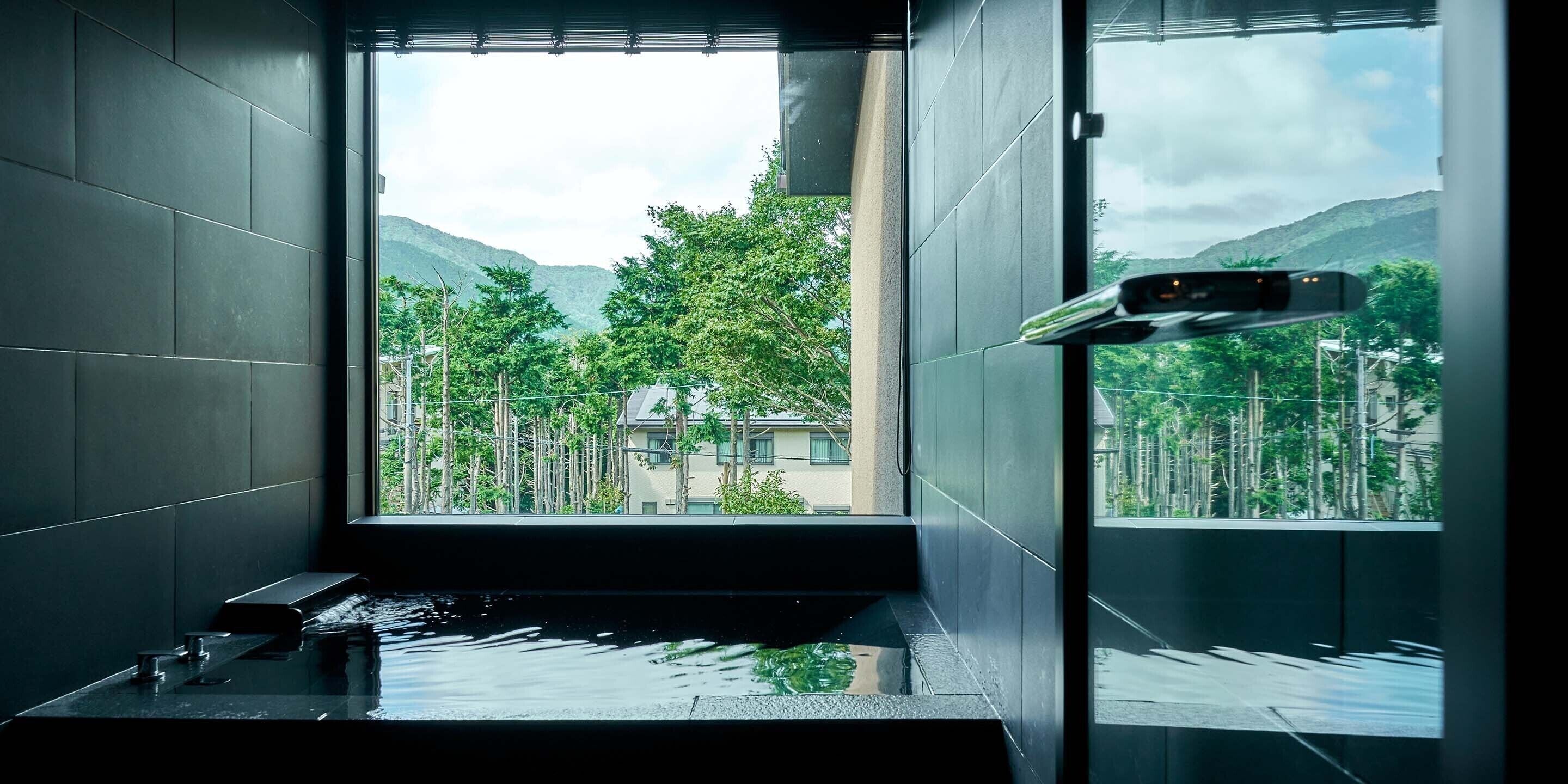 Un baño moderno con un ventanal grande, una bañera y zona de ducha.