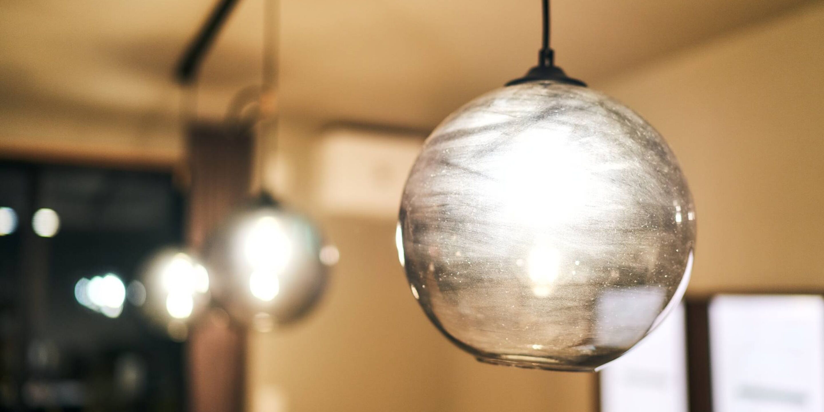 A close-up of a hanging spherical light fixture with a reflective surface.