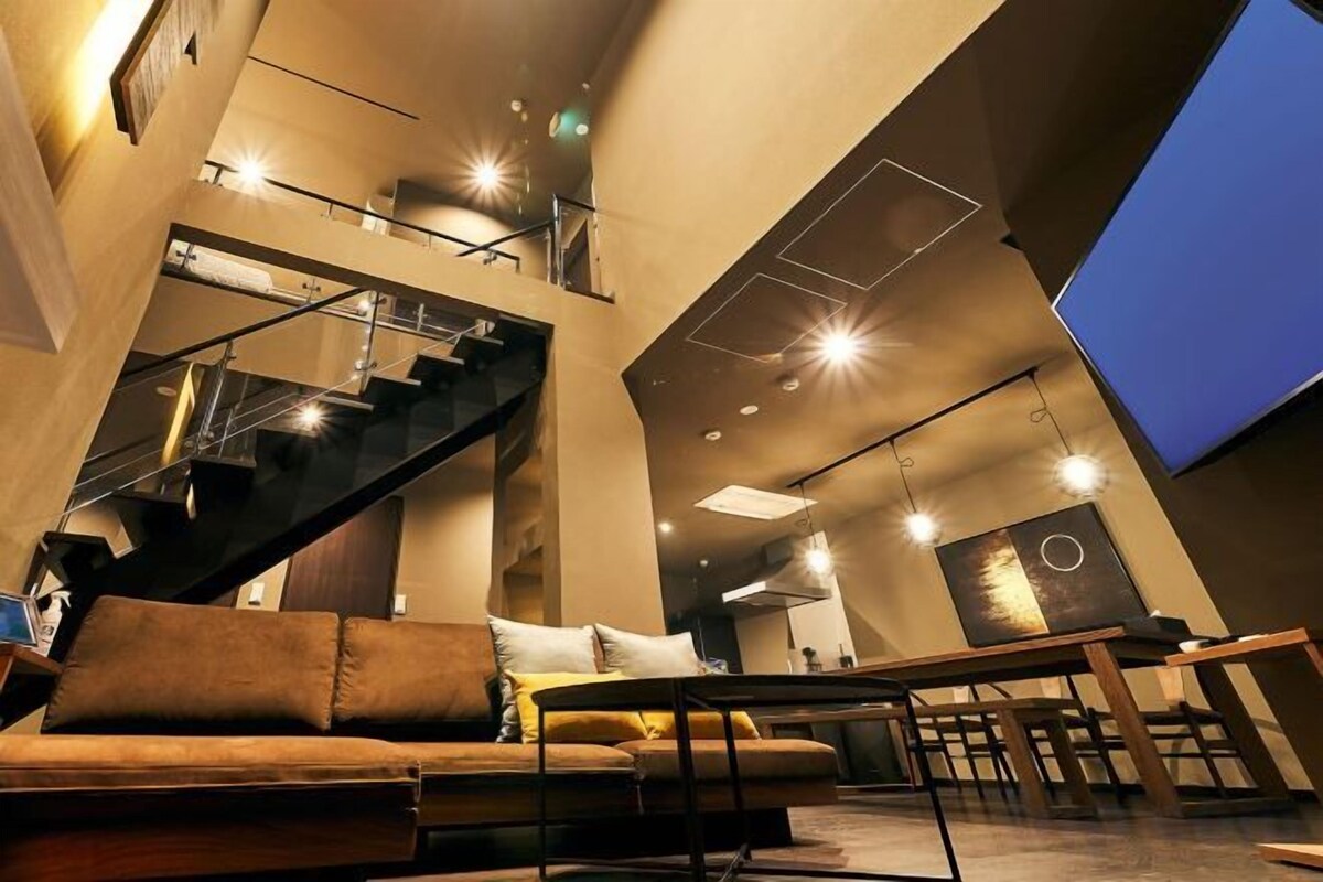 A modern interior with a staircase, a sofa, and a dining area.