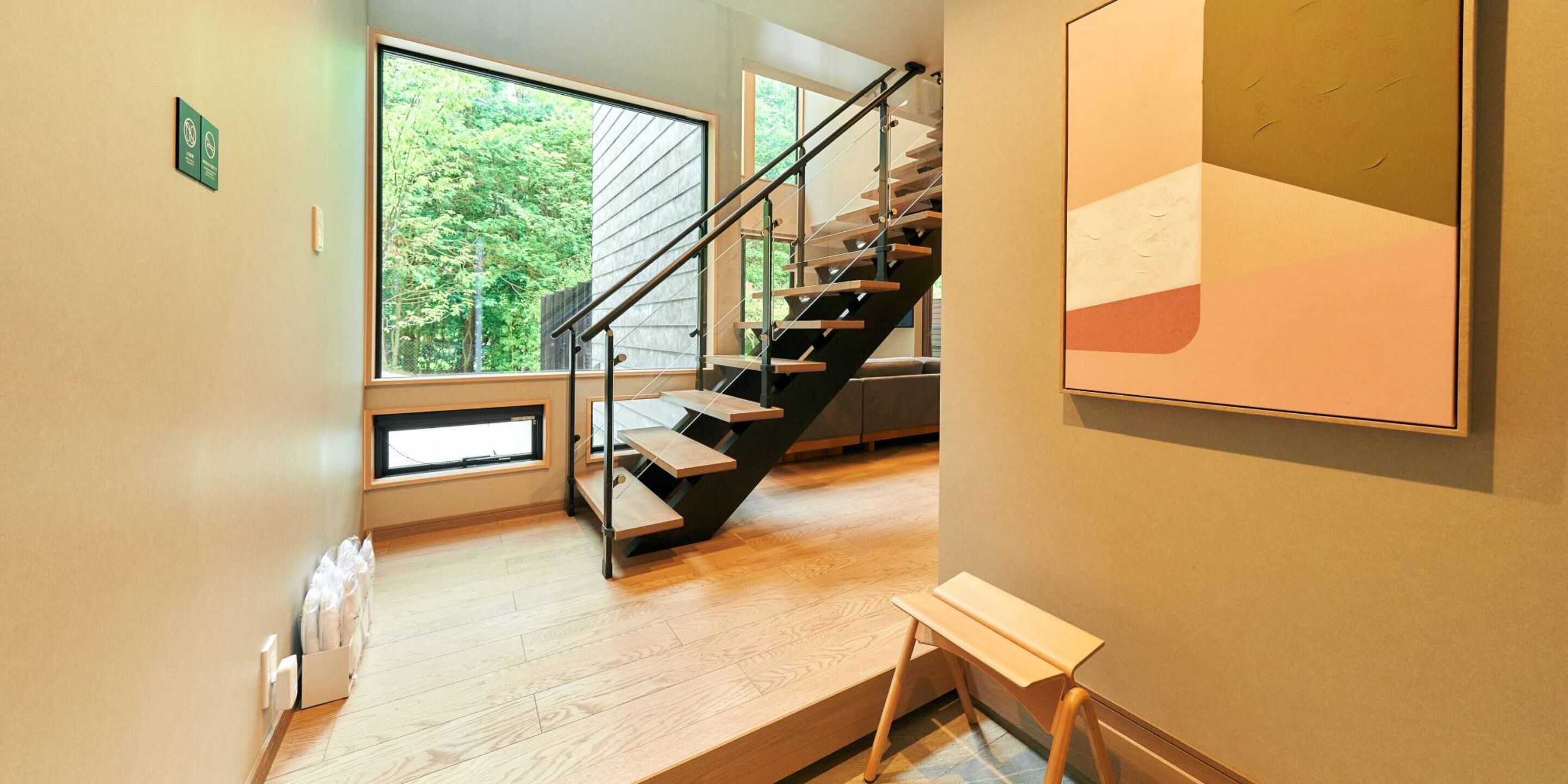 Un interior moderno con una escalera de madera, ventanas amplias y un diseño minimalista.