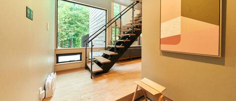 Un interior moderno con una escalera de madera, ventanas amplias y un diseño minimalista.