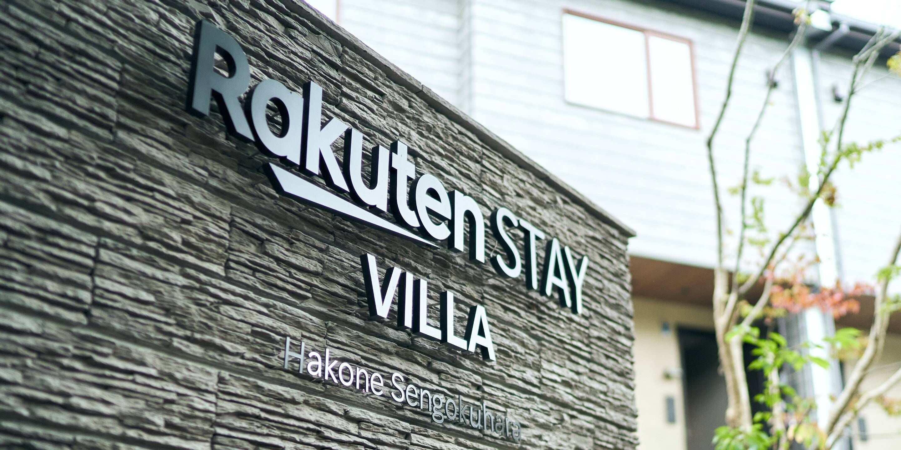 Een bordje met 'Rakuten Stay Villa', met een achtergrond van een gestructureerde muur.
