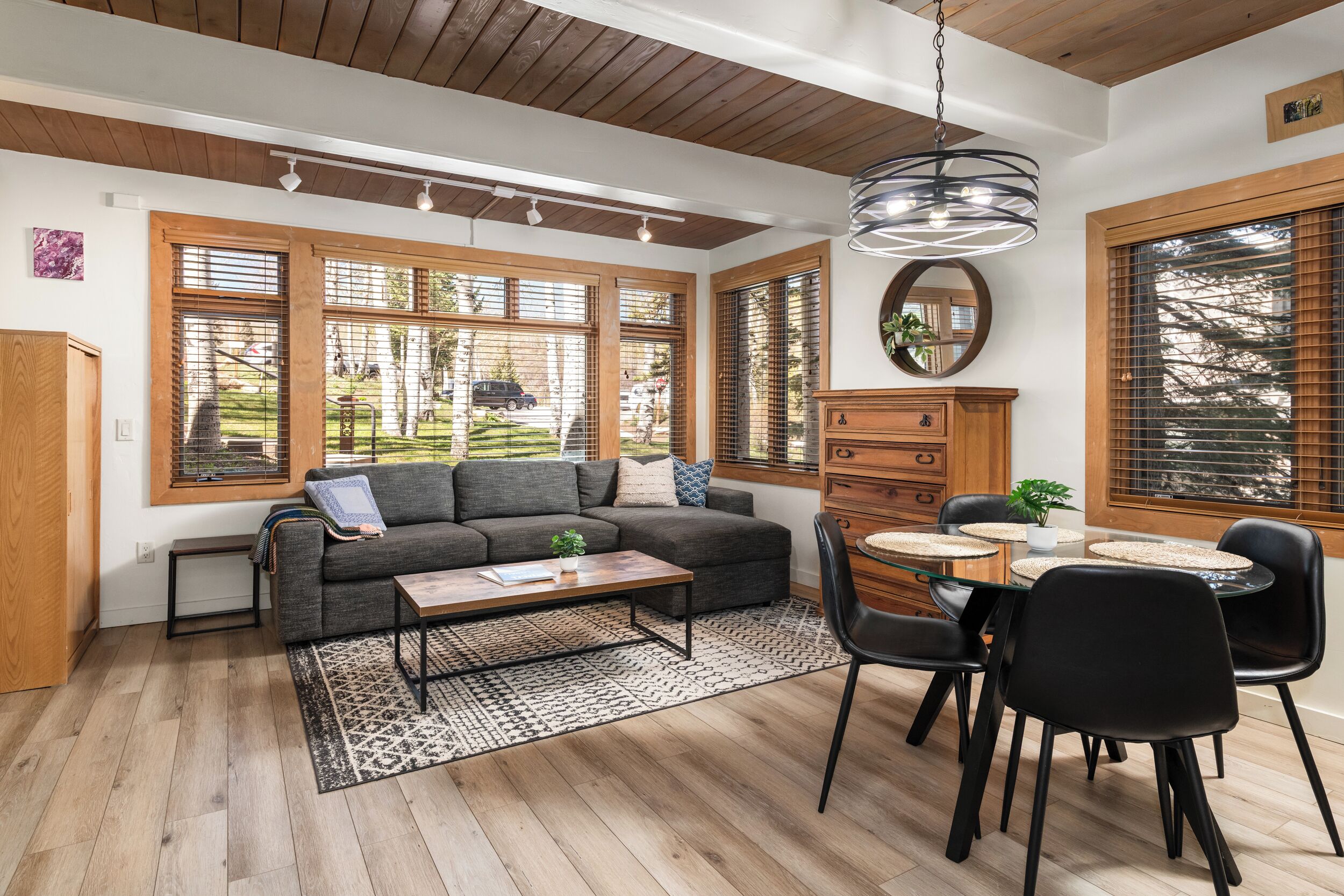 Un salon moderne comprenant un canapé, une table basse et un coin repas avec des chaises.