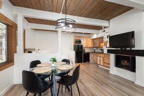 A modern kitchen with wooden cabinets, a flat-screen TV, and a fireplace. - Charming slopeside condo with pool (Snowmass Village)
