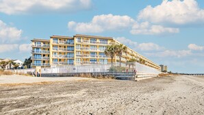 Hotel com vários andares e varandas, próximo a uma praia.
