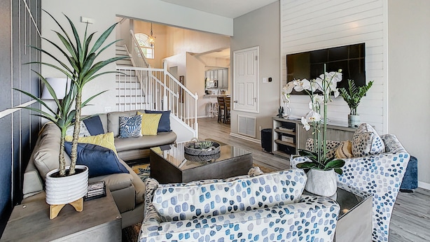 A modern living room with a sofa, coffee table, and potted plants. - Windsor Hills: Sleeps 10, Pool, Spa, Game Room (Kissimmee)