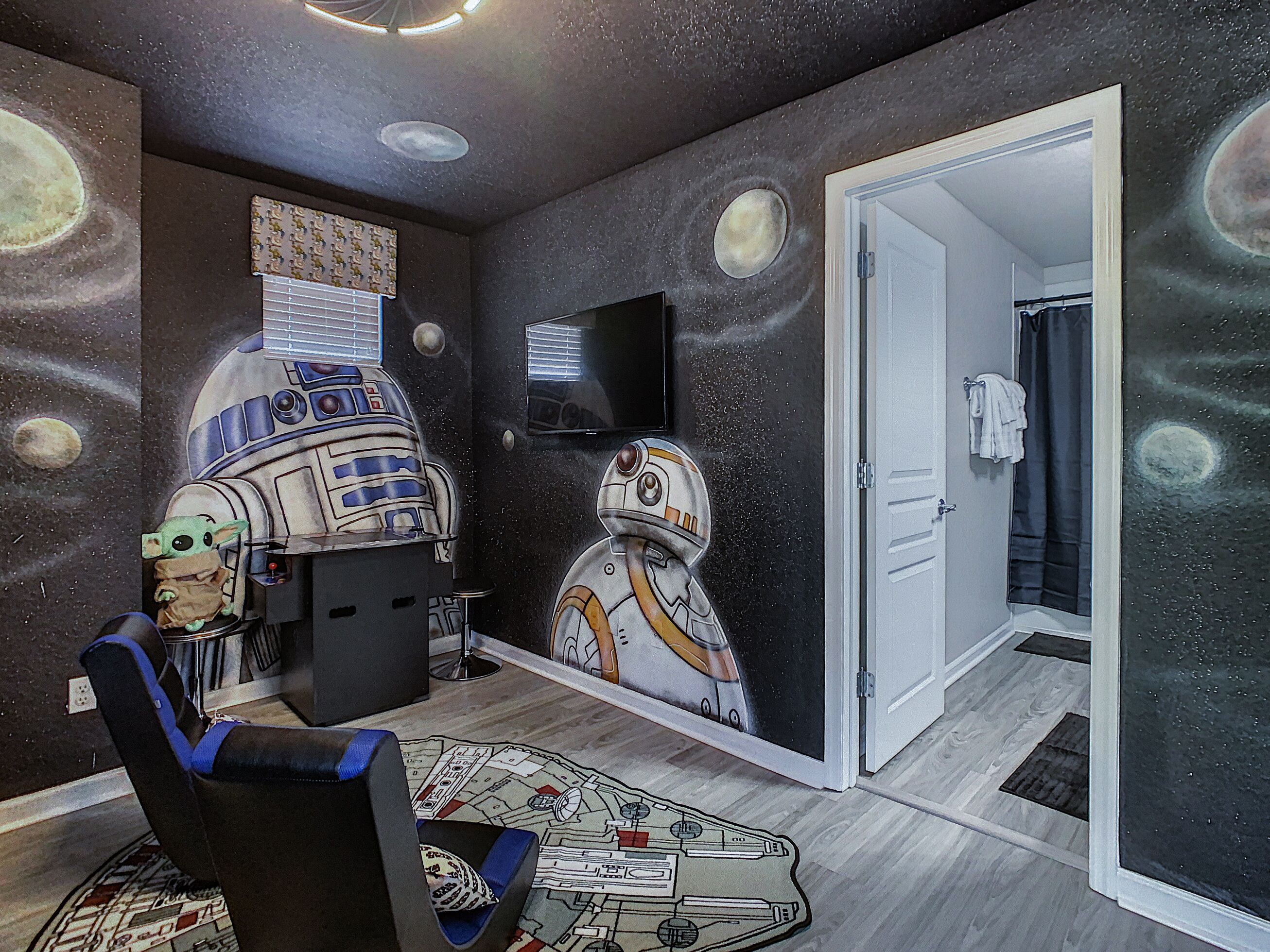 A room with a space-themed wall mural, a Star Wars character, and a Star Wars-themed rug.