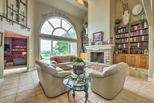 Relax by the fireplace in this cozy living room with a view of the outdoors, featuring a bookshelf and two comfortable sofas.