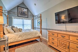 Relax in this serene bedroom with a four-poster bed, dresser, and wall-mounted TV.