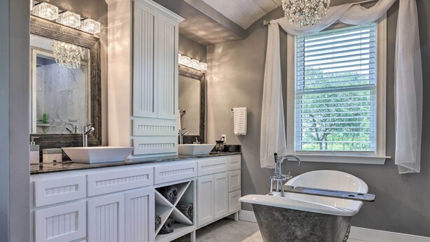 A modern bathroom with a freestanding bathtub, a large vanity with a vessel sink, and a large mirror. - Cozy Spring Branch Cottage in Hill Country! (Spring Branch)