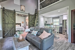 Relax in this inviting living area with a comfortable sofa, coffee table, and staircase leading to a kitchen and adjacent bedroom.