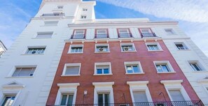 A multi-story building with a white facade and red brick accents.