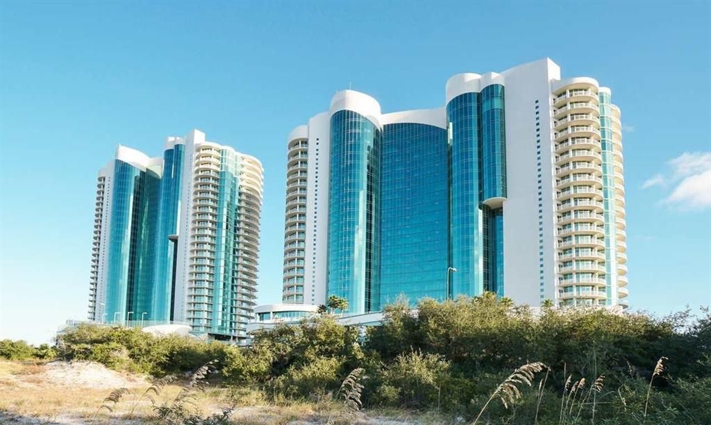 Un hôtel à plusieurs étages au design moderne, caractérisé par une façade en verre imposante et de nombreux balcons.