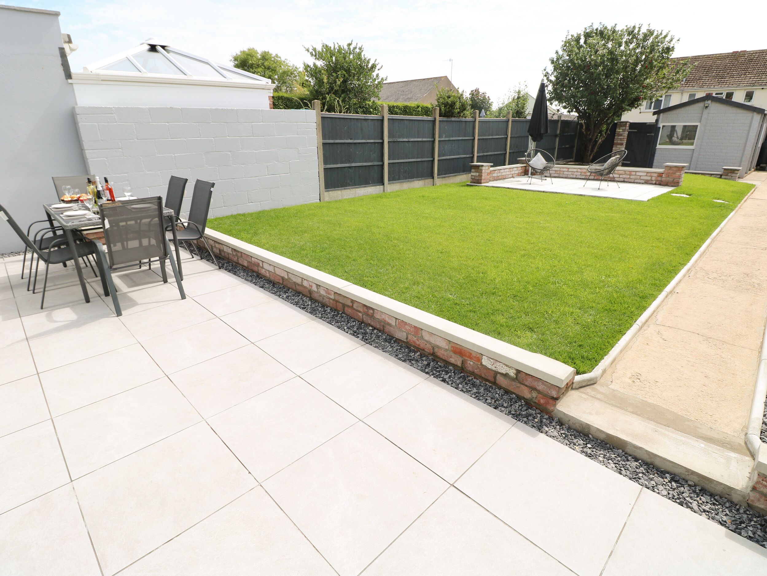 A backyard with a patio, a dining table with chairs, and a grassy lawn.