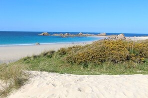 A beach with clear blue water, sandy shore, and rocky outcrops in the distance. - Vacation home a few steps from the beach: A la maison de Goulannou (Tréflez)