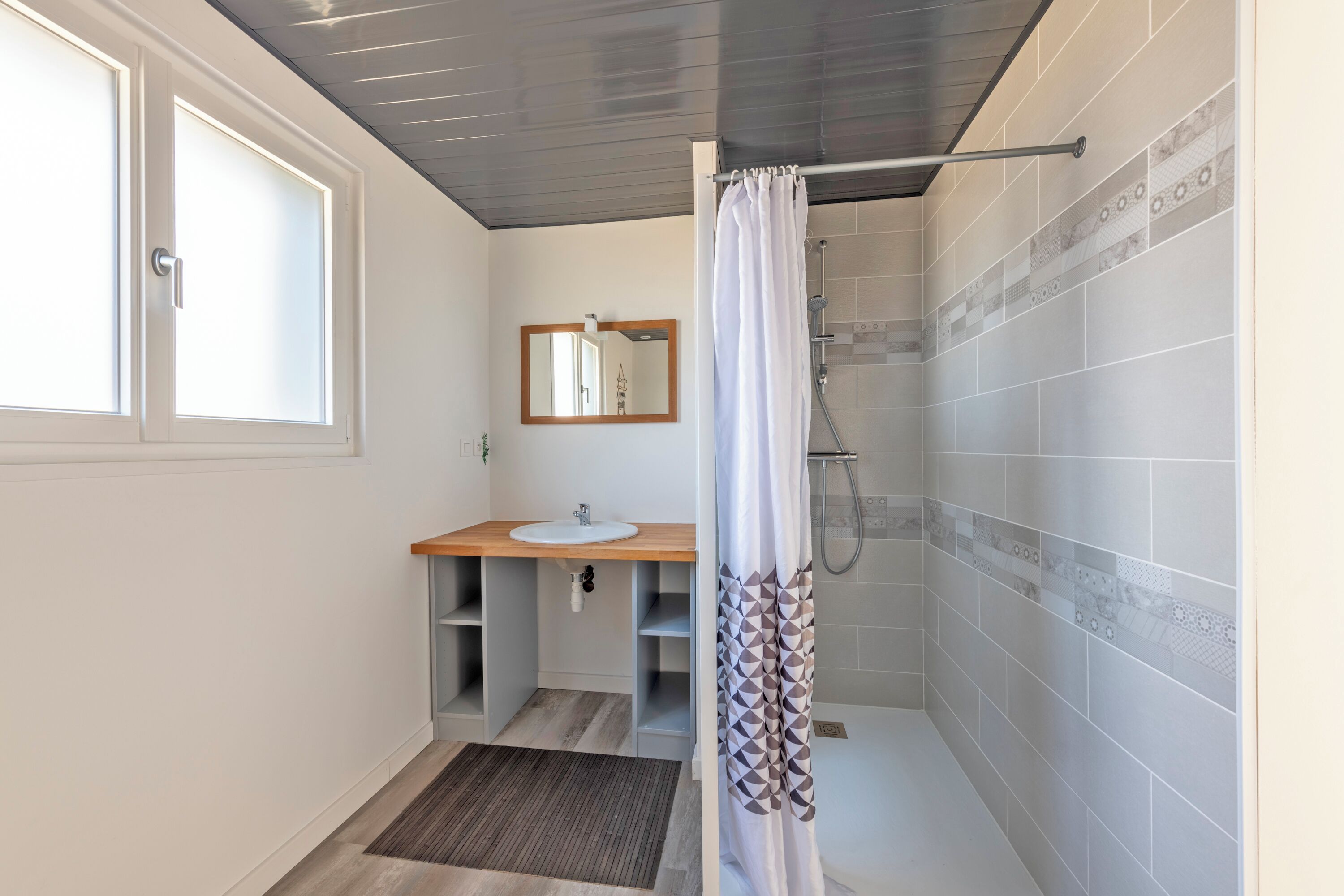 A bathroom with a shower, a sink, and a mirror.