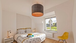 A bedroom with a bed, bedside tables, a lamp, a window with a view, and a chair.