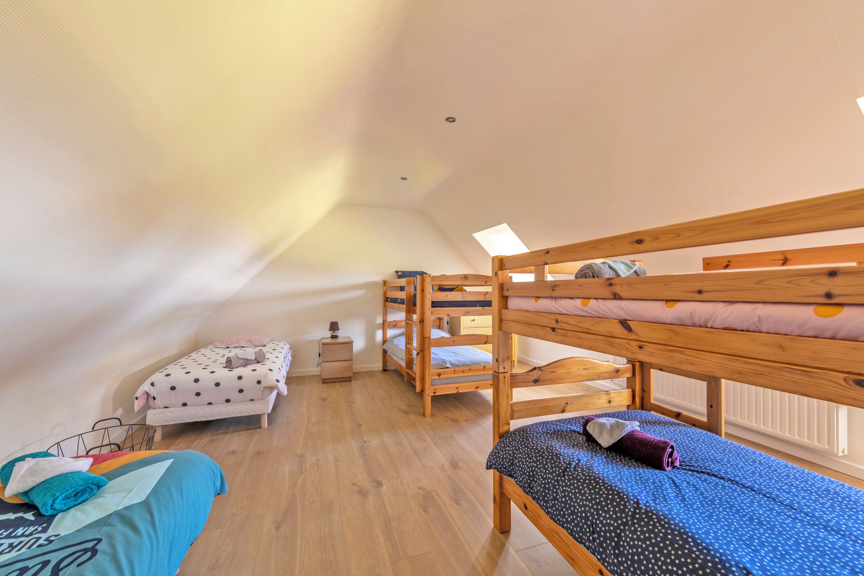 Una habitación tipo dormitorio con literas, un escritorio pequeño y una ventana.