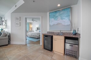 A modern kitchen with a dishwasher, refrigerator, and a large painting above the counter.
