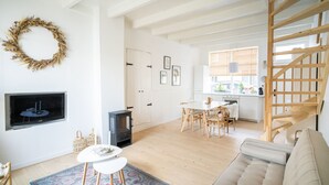 A modern living room with a fireplace, a dining area, and a staircase.