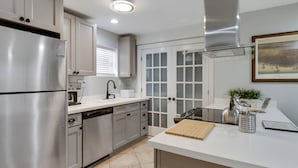 A modern kitchen with stainless steel appliances, a white countertop, and a view of the city through large windows. - Canal DOWN |Streetcar Line MidCity| Add More Space (New Orleans)