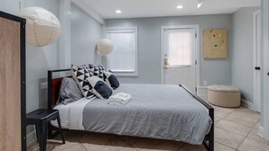 A bedroom with a bed, bedside tables, a chair, and a door. - Canal DOWN |Streetcar Line MidCity| Add More Space (New Orleans)