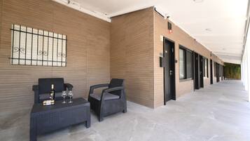 A modern hotel lobby with a reception desk, seating area, and a corridor leading to rooms.