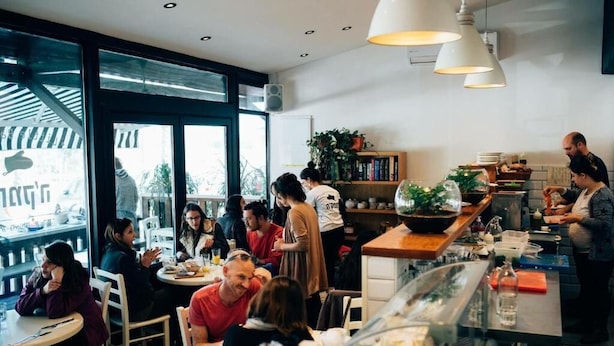 A restaurant with round tables, a counter with a chef, and large windows.