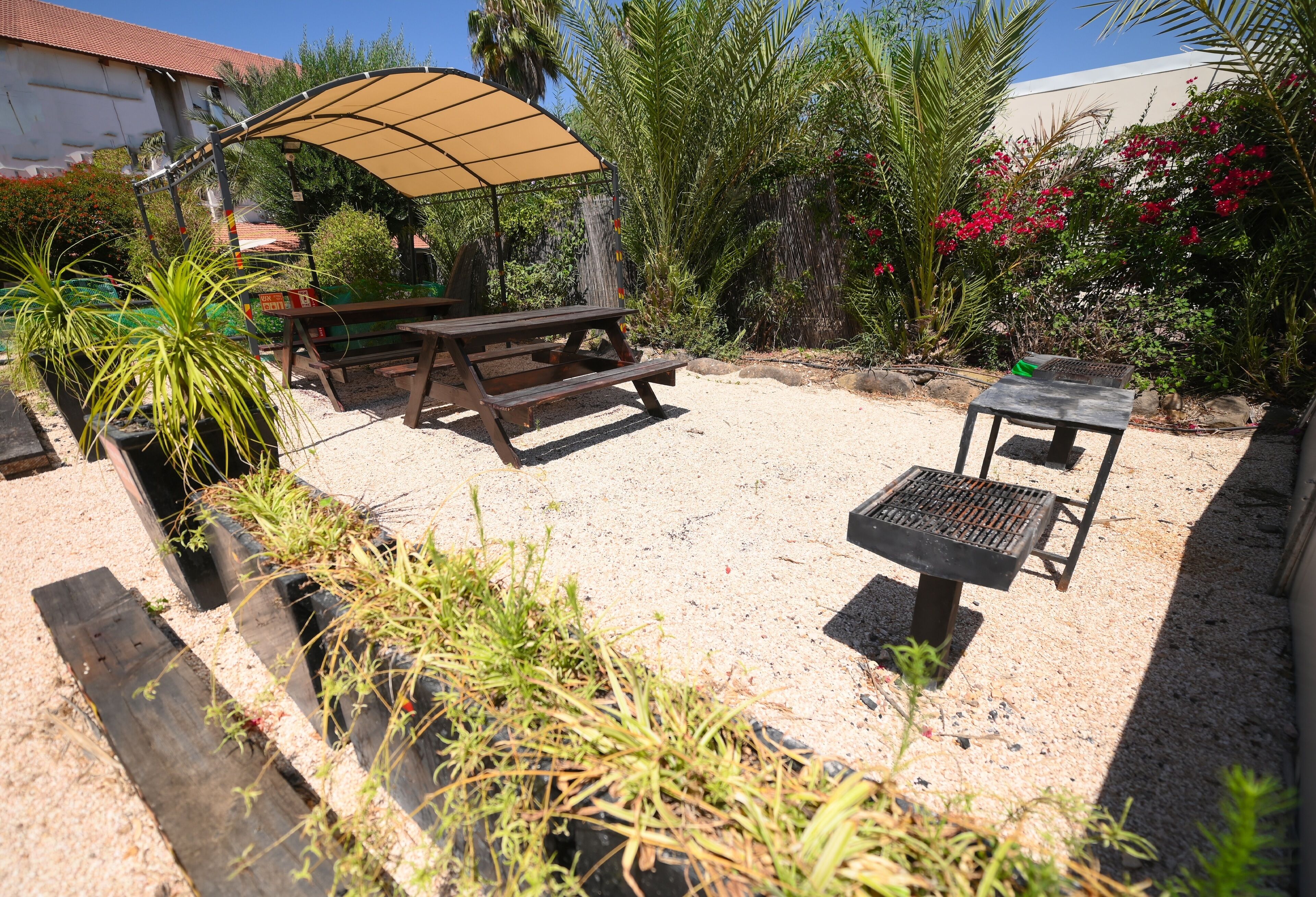 An outdoor patio with a picnic table, a barbecue grill, and a shaded area.